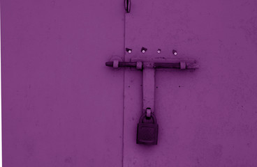 Padlock on metal gate in purple tone.