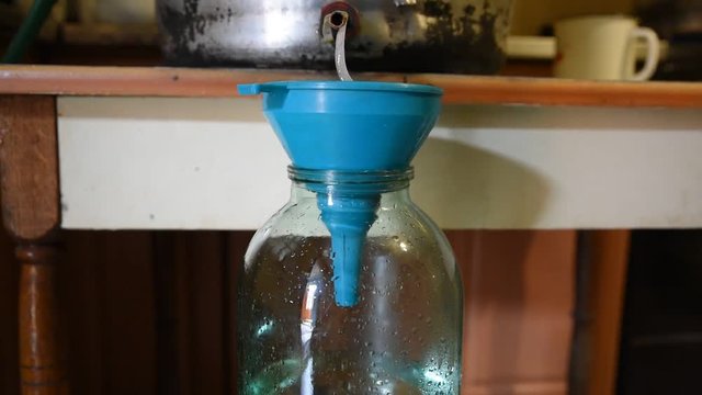 Pair is converted into a vodka, at the exit of the cooling system. The filtration moonshine and collection stage in a glass jar. Preparation moonshine at home, distillation process
