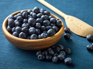 Closeup of fresh blueberry fruit in a wooden plate.