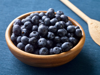 Closeup of fresh blueberry fruit in a wooden plate.