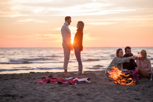 Couple enjoying with friends at sunset on the beach