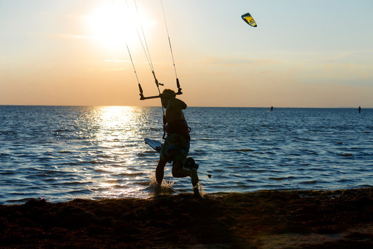 professional kitter runs with a board in the hands amid a beautiful sunset