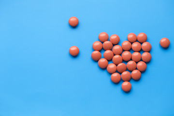 The heart made of tablets  on blue background. Pills with copyspace