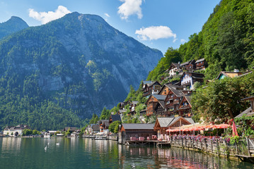 Fototapeta premium Classic postcard view of famous Hallstatt lakeside town reflecting in Hallstattersee lake in the Austrian Alps in scenic beautiful sunny day in summer, Salzkammergut region, Austria. Neutral colors.