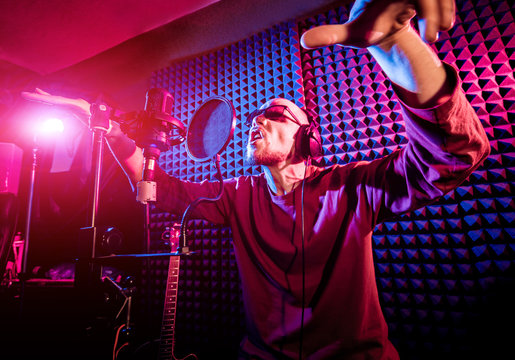 The singer sings with a microphone in the recording studio.