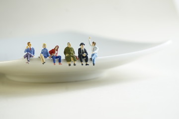 A group of miniature figures of people sitting on a plate and discussing problems.
