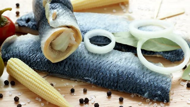 Saltwater marinated fish, cold appetizer. Herring fillet marinated on wooden cutting board