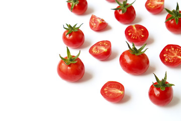 Bunch of beautiful juicy organic red cherry tomatoes whole & halved on white background. Top view of shiny polished vegetables. Clean eating concept. Vegetarian vegan detox diet. Copy space, flat lay.