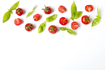 Bunch of beautiful juicy organic red cherry tomatoes, green basil leaves on white background. Shiny polished glossy vegetables. Clean eating concept. Vegetarian diet. Copy space, flat lay, top view.