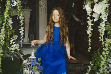 happy little girl holding decorative bird cage full of flowers. Studio shot in provence style interior