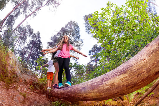 Group of kids walking over the long big wood log