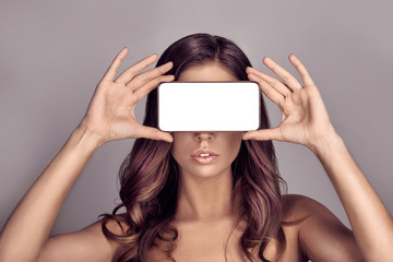 Portrait of pretty woman covering her eyes with smartphone