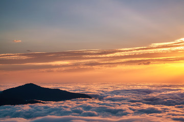 Mountain silhouette above the clouds at sunrise, view from the top view of mountains.