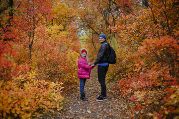 Fototapeta premium portrait of pretty little girl and young father walking in beautiful autumn park