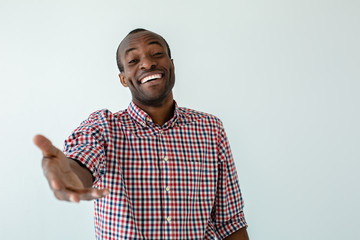 Joyful afro american man holding his hand ahead