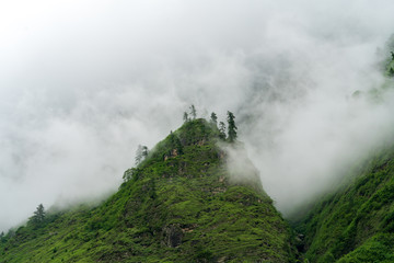 A tall foothill peaks through the clouds during monsoon season on the Annapurna Circuit