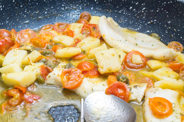 Fototapeta na wymiar cod cooked in a pan, with tomato, potatoes and capers