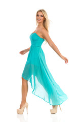 Naklejka premium Fashion Model In Turquoise Dress Is Walking And Looking At Camera