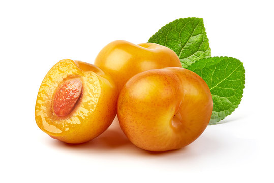 Juicy yellow plums and a half of yellow plum fruit with leaves, isolated on white background.