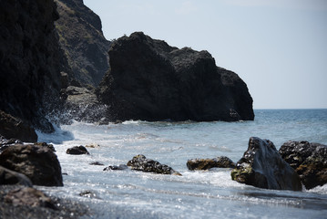 Rocky seashore with waves on a bright sunny day.