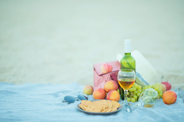 Picnic background with bag, grape and white wine on the beach by blue sea