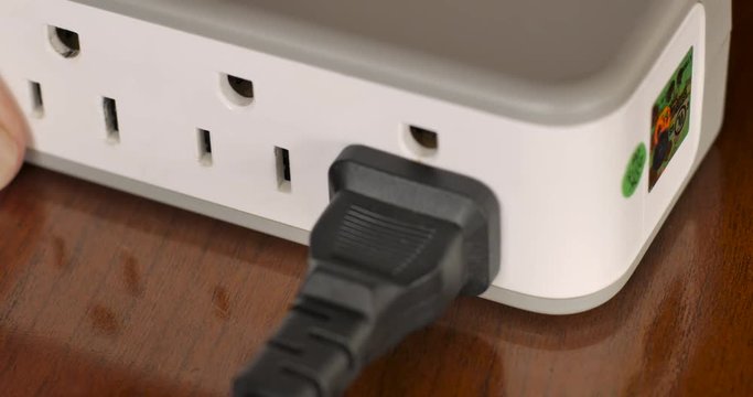 Hand plugging in a polarized unground NEMA AC power plug into an adapter