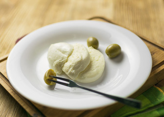 Cheese mozzarella and olives on a plate on a wooden background.