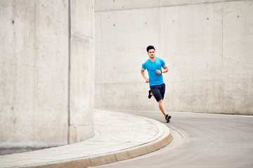 Athletic man running on road in the city. Outdoors training concept