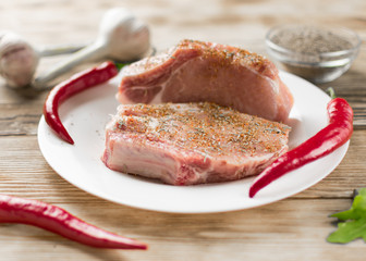 Raw pork ribs with red pepper, garlic and seasonings on a wooden background.