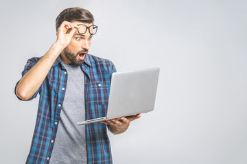 Wtf?! Omg! Oh no! Young amazed emotional brunet with bristle with sad grimace looks at screen of device, he can`t believe the bad news he received, gesturing with palms of arms.
