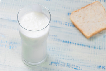 Kefir, yogurt in a glass on a background of slices of white bread on a wooden background.