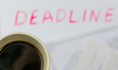 Procrastination concept: Drink coffee, when you can already see deadline. A cup of coffee on the...