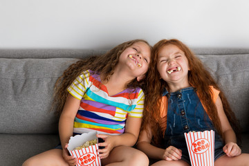 Young girls making silly faces with pop corn in their mouth
