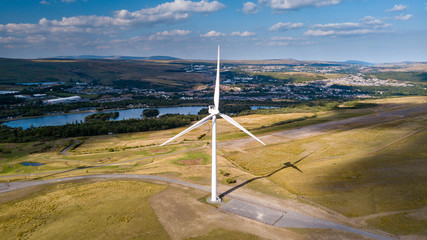 A large wind turbine on a rural hillside next to a lake