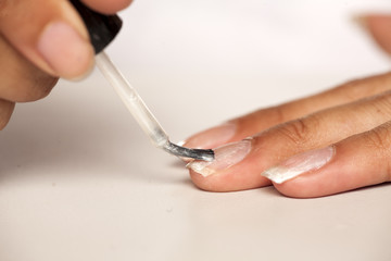 closeup of dark skinned woman polishing her finger nails on white background