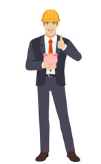 Businessman in construction helmet holding a piggy bank and showing thumb up