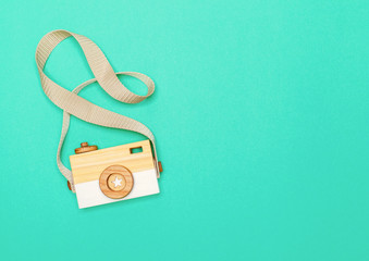 view from above on a wooden children's handmade camera on a bright colored paper background with space for text. flat lay