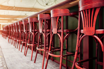Empty cafe. Wooden chairs beside bar counter. Red vintage seats in row