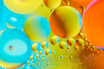 Beautiful color abstract background from mixied water and oil. Pastel colored abstraction. Yellow, orange and blue background from water bubbles.