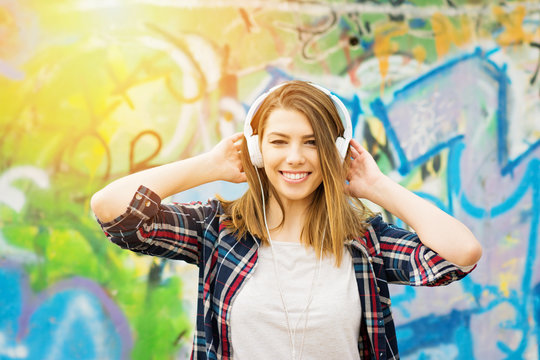 Happy young woman with headphones enjoying listening to music. Natural lighting, closeup, retouched.