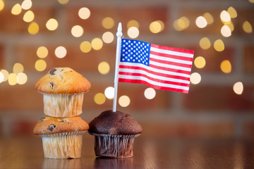 Homemade classic cupcakes and flag of the United States with fairy lights in bokeh.
