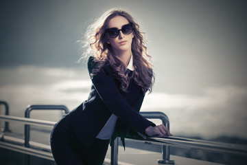 Young fashion blond business woman in sunglasses walking in city street