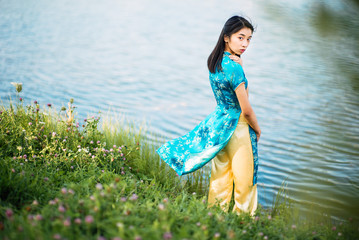 Beautiful young Asian girl outdoors, Ao dai - famous traditional costume for a woman in Vietnam