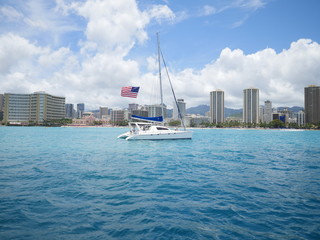 a sail boat with american flag in front of Waikiki beach Honolulu Hawaii