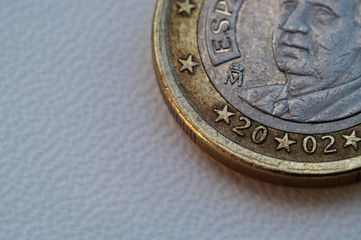 One euro coin on white textured background. The coin is in the upper right corner.