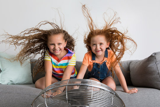 Young girls with floating hair playing with fan
