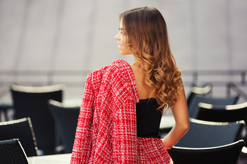 Young fashion woman in red tweed jacket and skirt suit at sidewalk cafe