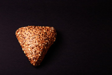 Dark bun with seed on black background. Text space