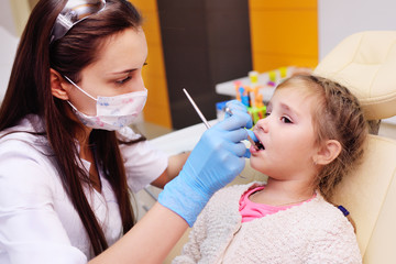 The dentist examines a child's teeth in a dental chair.