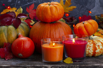 Fall ripe of pumpkins with glowing candles on wooden table